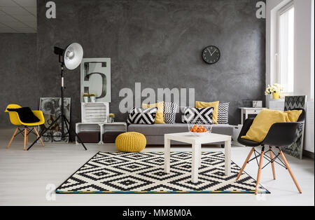 Stylische, geräumige Wohnzimmer mit grauen Wände und schwarze, weiße und gelbe Dekorationen Stockfoto