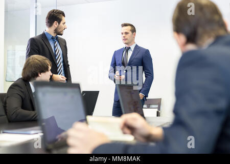 Erfolgreiche Teamleiter und Unternehmer führt informelle interne Business-Meeting. Geschäftsmann, arbeiten am Laptop im Vordergrund. Geschäfts- und entrep Stockfoto