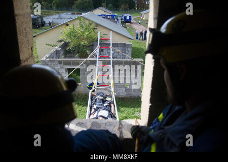 Mitglieder der Bundesanstalt Technisches Hilfswerk in Frankenthal, Deutschland, eine zivile Organisation, einem verletzten Mannequin role-Player von einem Dach während Training Cobra Strike 17 von Charlie Company, 457th zivilen Angelegenheiten Bataillon, in Wackernheim, Deutschland, Sept. 16, 2017 led-Extrakt. Diese lokale multi-partnered Übung tests Bewertung Fähigkeiten zivile Angelegenheiten Lote' in einer fiktiven nach der Erdbebenkatastrophe Szenario und Abstimmung mit den örtlichen Rettungsdienst (U.S. Armee finden Foto vom Kapitän Jeku Arce, 221St Public Affairs Distanz). Stockfoto