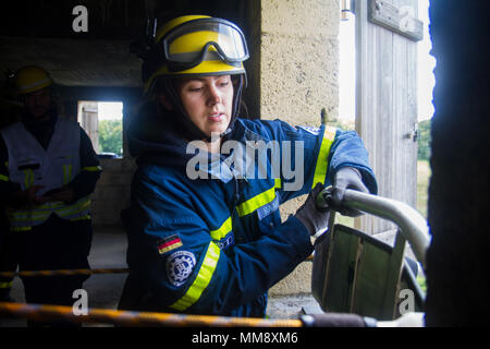 Mitglieder der Bundesanstalt Technisches Hilfswerk in Frankenthal, Deutschland, eine zivile Organisation, einem verletzten Mannequin role-Player von einem Dach während Training Cobra Strike 17 von Charlie Company, 457th zivilen Angelegenheiten Bataillon, in Wackernheim, Deutschland, Sept. 16, 2017 led-Extrakt. Diese lokale multi-partnered Übung tests Bewertung Fähigkeiten zivile Angelegenheiten Lote' in einer fiktiven nach der Erdbebenkatastrophe Szenario und Abstimmung mit den örtlichen Rettungsdienst (U.S. Armee finden Foto vom Kapitän Jeku Arce, 221St Public Affairs Distanz). Stockfoto