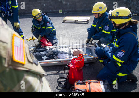 Ein Mitglied der Bundesanstalt Technisches Hilfswerk in Frankenthal, Deutschland, eine zivile Organisation, Vorbereitung einer verletzten Mannequin role-Player von einem Dach während Training Cobra Strike 17 von Charlie Company, 457th zivilen Angelegenheiten Bataillon, in Wackernheim, Deutschland, Sept. 16, 2017 Led zu extrahieren. Diese lokale multi-partnered Übung tests Bewertung Fähigkeiten zivile Angelegenheiten Lote' in einer fiktiven nach der Erdbebenkatastrophe Szenario und Abstimmung mit den örtlichen Rettungsdienst (U.S. Armee finden Foto vom Kapitän Jeku Arce, 221St Public Affairs Distanz). Stockfoto