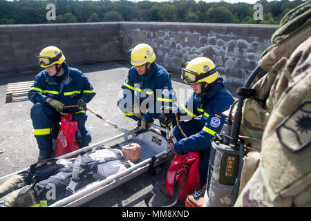 Ein Mitglied der Bundesanstalt Technisches Hilfswerk in Frankenthal, Deutschland, eine zivile Organisation, Vorbereitung einer verletzten Mannequin role-Player von einem Dach während Training Cobra Strike 17 von Charlie Company, 457th zivilen Angelegenheiten Bataillon, in Wackernheim, Deutschland, Sept. 16, 2017 Led zu extrahieren. Diese lokale multi-partnered Übung tests Bewertung Fähigkeiten zivile Angelegenheiten Lote' in einer fiktiven nach der Erdbebenkatastrophe Szenario und Abstimmung mit den örtlichen Rettungsdienst (U.S. Armee finden Foto vom Kapitän Jeku Arce, 221St Public Affairs Distanz). Stockfoto