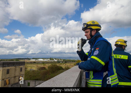 Ein Mitglied der Bundesanstalt Technisches Hilfswerk in Frankenthal, Deutschland, eine zivile Organisation, Radios Extraktion eines verletzten Mannequin role-Player von einem Dach während Training Cobra Strike 17 von Charlie Company, 457th zivilen Angelegenheiten Bataillon, in Wackernheim, Deutschland, Sept. 16, 2017 Led zu koordinieren. Diese lokale multi-partnered Übung tests Bewertung Fähigkeiten zivile Angelegenheiten Lote' in einer fiktiven nach der Erdbebenkatastrophe Szenario und Abstimmung mit den örtlichen Rettungsdienst (U.S. Armee finden Foto vom Kapitän Jeku Arce, 221St Public Affairs Distanz). Stockfoto