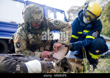 Staff Sgt. Paul Myers (links), medizinische Operationen Non-Commissioned Officer verantwortlich für Charlie Company (C Co.), 457Th zivilen Angelegenheiten Bataillon (CA MRD.), gilt eine Schiene auf einem verletzten mannequin Rolle-Player mit Hilfe von einem Mitglied der Bundesanstalt Technisches Hilfswerk in Frankenthal, Deutschland, eine zivile Organisation, während der Übung Cobra Strike 17 von C Co, 457Th CA BN, Wackernheim, Deutschland, Sept. 16, 2017. Diese lokale multi-partnered Übung tests Bewertung Fähigkeiten zivile Angelegenheiten Lote' in einer fiktiven nach der Erdbebenkatastrophe Szenario und Abstimmung mit den örtlichen Stockfoto