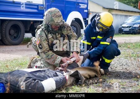 Staff Sgt. Paul Myers (links), medizinische Operationen Non-Commissioned Officer verantwortlich für Charlie Company (C Co.), 457Th zivilen Angelegenheiten Bataillon (CA MRD.), gilt eine Schiene auf einem verletzten mannequin Rolle-Player mit Hilfe von einem Mitglied der Bundesanstalt Technisches Hilfswerk in Frankenthal, Deutschland, eine zivile Organisation, während der Übung Cobra Strike 17 von C Co, 457Th CA BN, Wackernheim, Deutschland, Sept. 16, 2017. Diese lokale multi-partnered Übung tests Bewertung Fähigkeiten zivile Angelegenheiten Lote' in einer fiktiven nach der Erdbebenkatastrophe Szenario und Abstimmung mit den örtlichen Stockfoto