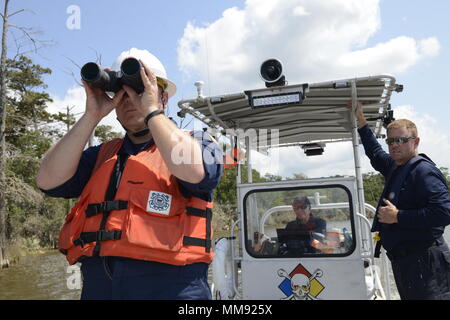 Coast Guard Chief Warrant Officer Russ Smith von den Golf Strike Team sucht für gefährliche Materialien und Container auf die San Jacinto River in Houston, Texas, am Freitag, den 15. September 2017, während Harris County Gefahrstoffe Response Team Mitglieder Bill Hand, Schiff, Pilot, und David Corbin, rechts, auf. Die Küstenwache eine Partnerschaft mit der Harris County Hazmat Team, Environmental Protection Agency, Texas National Guard, 6. zivile Support Team, Arkansas National Guard, 61. Zivile Support Team, Texas Kommission auf Umweltqualität, Texas General Land Office, und die Vertragspartner von Environme Stockfoto