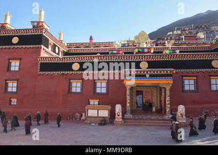 Tibetischen Pilger wandern Kora Kreise um den heiligen Bakong Schrift Druckmaschine Kloster in Dege, Sichuan, China Stockfoto