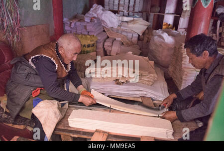 Arbeitnehmer das Schneiden von Papier in der heiligen Schrift Bakong Druckmaschine Kloster in Dege, Sichuan, China Stockfoto