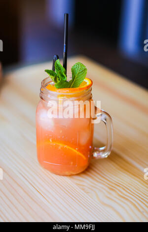 Glas Orangensaft mit Minze auf hölzernen Tisch im Café. Stockfoto