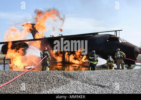 Mitglieder der Tulsa Feuerwehr (Tragen von Tan Bunker Gear) arbeiten mit einem Mitglied der 72nd Bauingenieur Squadron, Feuerwehr, während eine Schulungsveranstaltung mit einem full-size Flugzeugbrand Trainingsgerät Sept. 13, 2017, Tinker Air Force Base, Oklahoma. Die Tulsa Feuerwehrmänner waren Gäste der 72nd Bauingenieur Squadron, Feuerwehr, die Rezertifizierung unterzogen wurde. (U.S. Air Force Foto/Greg L. Davis) Stockfoto