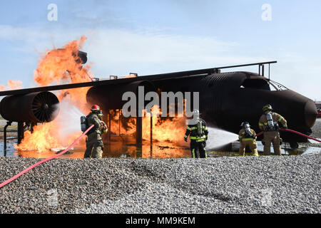 Mitglieder der Tulsa Feuerwehr (Tragen von Tan Bunker Gear) arbeiten mit einem Mitglied der 72nd Bauingenieur Squadron, Feuerwehr, während eine Schulungsveranstaltung mit einem full-size Flugzeugbrand Trainingsgerät Sept. 13, 2017, Tinker Air Force Base, Oklahoma. Die Tulsa Feuerwehrmänner waren Gäste der 72nd Bauingenieur Squadron, Feuerwehr, die Rezertifizierung unterzogen wurde. (U.S. Air Force Foto/Greg L. Davis) Stockfoto