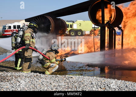 Mitglieder der Tulsa Feuerwehr (Tragen von Tan Bunker Gear) arbeiten mit einem Mitglied der 72nd Bauingenieur Squadron, Feuerwehr, während eine Schulungsveranstaltung mit einem full-size Flugzeugbrand Trainingsgerät Sept. 13, 2017, Tinker Air Force Base, Oklahoma. Die Tulsa Feuerwehrmänner waren Gäste der 72nd Bauingenieur Squadron, Feuerwehr, die Rezertifizierung unterzogen wurde. (U.S. Air Force Foto/Greg L. Davis) Stockfoto