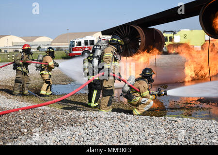 Mitglieder der Tulsa Feuerwehr (Tragen von Tan Bunker Gear) arbeiten mit einem Mitglied der 72nd Bauingenieur Squadron, Feuerwehr, während eine Schulungsveranstaltung mit einem full-size Flugzeugbrand Trainingsgerät Sept. 13, 2017, Tinker Air Force Base, Oklahoma. Die Tulsa Feuerwehrmänner waren Gäste der 72nd Bauingenieur Squadron, Feuerwehr, die Rezertifizierung unterzogen wurde. (U.S. Air Force Foto/Greg L. Davis) Stockfoto