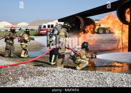 Mitglieder der Tulsa Feuerwehr (Tragen von Tan Bunker Gear) arbeiten mit einem Mitglied der 72nd Bauingenieur Squadron, Feuerwehr, während eine Schulungsveranstaltung mit einem full-size Flugzeugbrand Trainingsgerät Sept. 13, 2017, Tinker Air Force Base, Oklahoma. Die Tulsa Feuerwehrmänner waren Gäste der 72nd Bauingenieur Squadron, Feuerwehr, die Rezertifizierung unterzogen wurde. (U.S. Air Force Foto/Greg L. Davis) Stockfoto