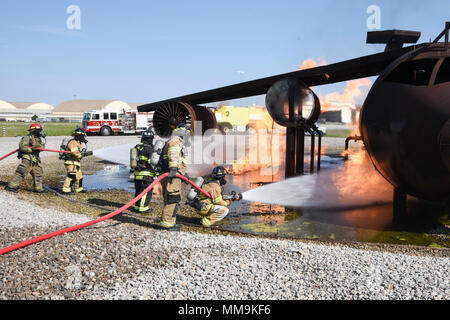 Mitglieder der Tulsa Feuerwehr (Tragen von Tan Bunker Gear) arbeiten mit einem Mitglied der 72nd Bauingenieur Squadron, Feuerwehr, während eine Schulungsveranstaltung mit einem full-size Flugzeugbrand Trainingsgerät Sept. 13, 2017, Tinker Air Force Base, Oklahoma. Die Tulsa Feuerwehrmänner waren Gäste der 72nd Bauingenieur Squadron, Feuerwehr, die Rezertifizierung unterzogen wurde. (U.S. Air Force Foto/Greg L. Davis) Stockfoto