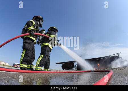 Zwei Mitgliedstaaten Teams aus dem 72. Bauingenieur Squadron, Feuerwehr, zusammen arbeiten, wie Sie das Flugzeug Feuer Trainingsgerät Sept. 13, 2017 Ansatz, Tinker Air Force Base, Oklahoma. Die Feuerwehrleute waren Durchführung jährlicher Rezertifizierung in der realistischen Umgebung. (U.S. Air Force Foto/Greg L. Davis) Stockfoto