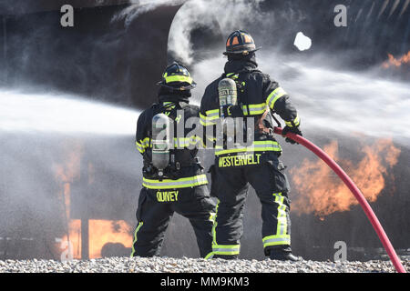 Zwei Mitgliedstaaten Teams aus dem 72. Bauingenieur Squadron, Feuerwehr, zusammen arbeiten, wie Sie das Flugzeug Feuer Trainingsgerät Sept. 13, 2017 Ansatz, Tinker Air Force Base, Oklahoma. Die Feuerwehrleute waren Durchführung jährlicher Rezertifizierung in der realistischen Umgebung. (U.S. Air Force Foto/Greg L. Davis) Stockfoto