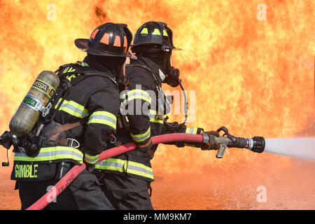 Zwei Mitgliedstaaten Teams aus dem 72. Bauingenieur Squadron, Feuerwehr, zusammen arbeiten, wie Sie das Flugzeug Feuer Trainingsgerät Sept. 13, 2017 Ansatz, Tinker Air Force Base, Oklahoma. Die Feuerwehrleute waren Durchführung jährlicher Rezertifizierung in der realistischen Umgebung. (U.S. Air Force Foto/Greg L. Davis) Stockfoto