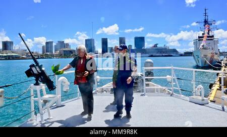 Leighton Tseu (links), Kane o ke Kai, segnet Coast Guard Cutter Oliver Berry (WPC 1124) Nach Ihrer Ankunft in Honolulu Sept. 22, 2017. William Anonsen, Coast Guard Foundation Trustee, und Leutnant Kenneth Frankling, kommandierender Offizier der Oliver Berry, begleitet ihn um die schnelle Reaktion Cutter. (U.S. Coast Guard Foto von Chief Petty Officer Sara Muir/Freigegeben) Stockfoto