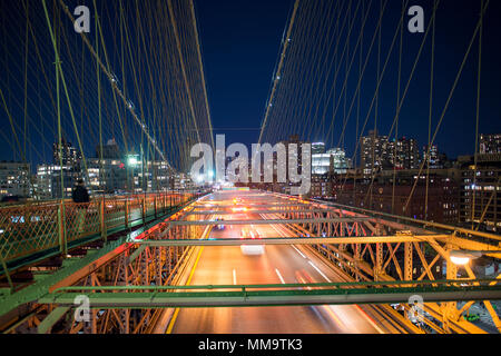 Lange Belichtung Bild von Autos vorbei über die beleuchteten Brooklyn Bridge bei Nacht. Im Hintergrund die Skyline von Manhattan, New York City, USA. Stockfoto