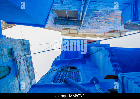 Ansicht von unten nach oben über einige traditionelle Häuser in einer kleinen Gasse in die blaue Stadt Jodhpur, Rajasthan, Indien. Stockfoto