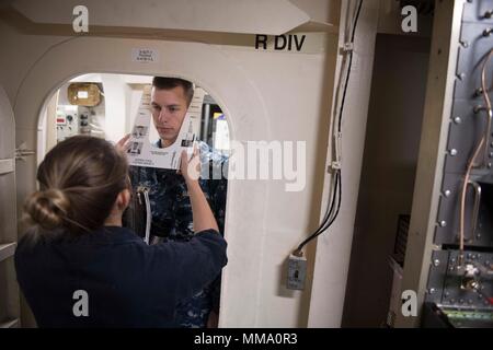 170922-N-IC 246-0032 Faslane, Schottland (Sept. 22, 2017) Maschinen Handwerker 2. Klasse Sierra Kaibel nimmt Fähnrich Taylor Withiam's, die administrative Aufteilung Officer, Messungen für ein M 50 chemischen, biologischen und radiologischen Maske an Bord der Arleigh-Burke-Klasse geführte-missile Destroyer USS Winston S. Churchill (DDG81) Sept. 22, 2017. Winston S. Churchill, homeported in der Naval Station Norfolk, ist die Durchführung von naval Operations in den USA 6 Flotte Bereich der Maßnahmen zur Unterstützung der US-amerikanischen nationalen Sicherheitsinteressen in Europa. (U.S. Marine Foto von Mass Communication Specialist Seaman Apprentice Ray Stockfoto