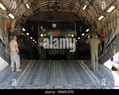 Flieger an die 183 d Airlift Squadron und Fliegern, die 172 d Logistik Bereitschaft Squadron eine schwere Erweiterte Mobilität taktische Fahrzeug an die 185 Aviation Brigade in Jackson, Fräulein zu einem C-17 Globemaster III bei Thompson Feld, Jackson, Miss., Sept. 28, 2017 Assigned Load zugeordnet. Die C-17 geladen zwei Armee Fahrzeuge nach St. Thomas um geliefert werden Bei der Wiederaufbau nach dem Hurrikan Maria. (U.S. Air National Guard Foto von älteren Flieger Kiara N. Spann) Stockfoto