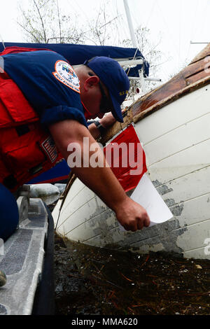 Petty Officer 2nd class Eddie Gallegos, ein Mitglied der Küstenwache Golf Strike Team, Orte eine Bewertung Aufkleber auf einem vertriebenen Schiff Boot Key Hafen, in der Nähe von Marathon, Florida, Sept. 29, 2017. Weitere Informationen für Schiffseigner daran interessiert, ihr Boot entfernen bei Http://myfwc.com/boating/vessel-hotline/removal/. U.S. Coast Guard Foto von Petty Officer 2. Klasse David Weydert. Stockfoto