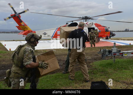 U.S. Coast Guard Investigative Service Agenten und taktische Strafverfolgungsbehörden Team Süd, Miami, Besatzungsmitglieder Last der Küstenwache MH-60 Jayhawk Helikopter von Air Station Clearwater, Florida, mit Nahrung und Wasser für die Bewohner in Utuado, Puerto Rico, Sept. 29, 2017. Als Teil der Abteilung für Homeland Security Team, die Küstenwache ist direkt an das FEMA und die gesamte Bundesregierung Hurrikan Recovery Phase der Reaktion auf den Hurrikan Maria verbunden. (U.S. Coast Guard Foto von Petty Officer 2nd class Meredith Manning) Stockfoto