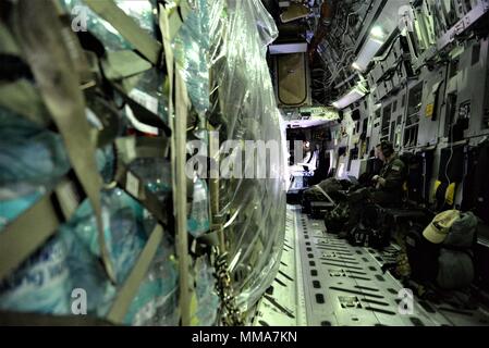 Die 3d-Luftbrücke der Squadron erreichen 7170 Crew Mitglieder Mitarbeiter Sgts. Herbert Scott, 736Th Aircraft Maintenance Squadron flying Crew Chief und Jakob Wright, 3d als Lademeister, Fahrt mit Nahrung und Wasser in einer C-17 Globemaster III das Hurricane Überlebenden von San Juan Luis Muñoz Marín Flughafen in San Juan, Puerto Rico verteilt werden, an Sept. 30, 2017. Reach 7170 gelieferten 118 tausend Pfund von Mahlzeiten bereit zu Essen und Mineralwasser in einem verwüsteten Puerto Rico mit Hilfe der Flieger aus der 123 Contingency Response Group verteilt werden. (U.S. Air Force Foto von Tech. Sgt. Matt Davis) Stockfoto