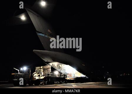 Die 3d-Luftbrücke der Squadron erreichen 7170 Crew und 123 Contingency Response Group Flieger entladen Essen und Wasser aus einem C-17 Globemaster III der Hurrikan Überlebenden von San Juan Luis Muñoz Marín Flughafen in San Juan, Puerto Rico verteilt werden, an Sept. 30, 2017. Reach 7170 gelieferten 118 tausend Pfund von Mahlzeiten bereit zu Essen und Mineralwasser in einem verwüsteten Puerto Rico mit Hilfe der Flieger aus der 123 Contingency Response Group verteilt werden. (U.S. Air Force Foto von Tech. Sgt. Matt Davis) Stockfoto