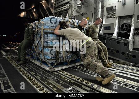 Die 3d-Luftbrücke der Squadron erreichen 7170 Crew und 123 Contingency Response Group Flieger entladen Essen und Wasser aus einem C-17 Globemaster III der Hurrikan Überlebenden von San Juan Luis Muñoz Marín Flughafen in San Juan, Puerto Rico verteilt werden, an Sept. 30, 2017. Reach 7170 gelieferten 118 tausend Pfund von Mahlzeiten bereit zu Essen und Mineralwasser in einem verwüsteten Puerto Rico mit Hilfe der Flieger aus der 123 Contingency Response Group verteilt werden. (U.S. Air Force Foto von Tech. Sgt. Matt Davis) Stockfoto