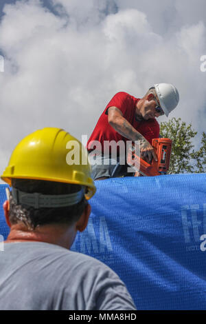 Operation Blue Roof ist ein Programm des US Army Corps of Engineers, das nach Hurrikanen provisorische Dachverkleidungen aus Kunststoff bereitstellt. Das Archivbild dokumentiert Bauunternehmer, die am 1. Oktober 2017 einen Furzstreifen und eine Plastikfolie an ein vom Sturm beschädigtes Haus in Sebring, Florida, als Teil der Erholung nach dem Hurrikan Irma nagelten. Stockfoto