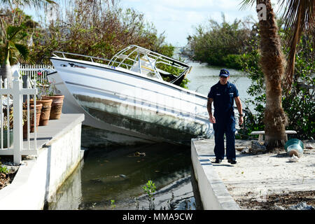 Petty Officer 1st Class Brian Moehler, ein Mitglied der atlantischen Strike Team, in Fort Dix, New Jersey liegt, prüft ein vertriebenen Schiff in einen Kanal auf Sugarloaf Key, Florida, Oktober 2, 2017. Bewertet Schiffe sind für Ausbau auf ihre Bedrohung für die Umwelt und ihre Gefahr zur Navigation priorisiert. U.S. Coast Guard video von Petty Officer 2. Klasse David Weydert. Stockfoto