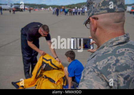 Us-Luftwaffe Kapitän Theodore Fox schnappt ein Bild der US-Armee Sgt. 1. Klasse Brian Karst, ein Mitglied der US-Armee goldene Ritter Fallschirm Team, Verpackung sein Fallschirm neben seinem Sohn Sept. 30, 2017 McLaughlin Air National Guard Base, Charleston, W. Virginia. 2017 markiert den 70. Jahrestag der Gründung von McLaughlin Air National Guard Base und Yeager Flughafen, der zu Ehren von Brig genannt wurden. Gen. James McLaughlin und Brig. Gen. Chuck Yeager, respektvoll. (U.S. Air National Guard Foto von Airman Kaleb Vance) Stockfoto