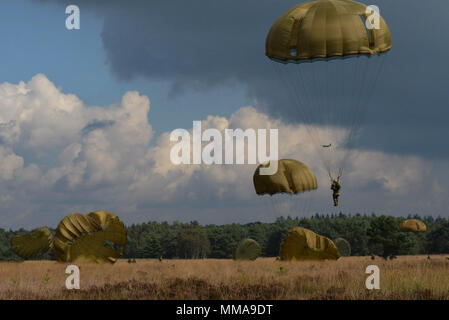 Fallschirm Vordächer füllen Sie den Himmel als Fallschirmjäger aus acht Ländern Land am Houtdorperveld Drop Zone während Falcon Sprung Sept. 15, 2017, Valkenburg, Niederlande. (U.S. Air Force Foto von Airman 1st Class Codie Collins) Stockfoto