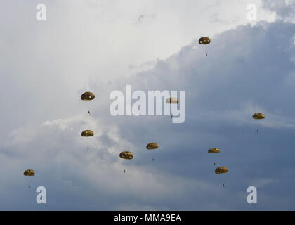 Fallschirm Vordächer füllen Sie den Himmel als Fallschirmjäger aus acht Ländern Land am Houtdorperveld Drop Zone während Falcon Sprung Sept. 15, 2017, Valkenburg, Niederlande. (U.S. Air Force Foto von Airman 1st Class Codie Collins) Stockfoto