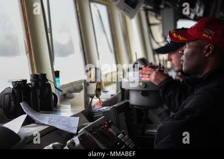 171001-N-RP 878-069 Faslane, Schottland (Okt. 2010) 1, 2017) Cmdr. Timothy Moore, kommandierender Offizier der Arleigh-Burke-Klasse geführte Anti-raketen-Zerstörer USS Donald Cook (DDG75), überwacht den Betrieb von der Brücke, wie das Schiff fährt Faslane, Schottland, in der Übung gewaltige Schild 2017, Okt. 1 zu beteiligen. Dieses Schild ist in den USA eine 6. Flotte-led, Naval auffällig und Unterstützung der Kräfte der NATO-Übung durchgeführt, die Verbesserung der Interoperabilität der Alliierten in einem live-fire integrierte Luft- und Raketenabwehr Umwelt, den Einsatz der NATO Command und Control reporting Strukturen. (U.S. Marine Foto von Masse Kommunikat Stockfoto