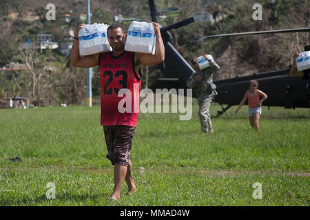 Bürger von Jayuga Essen und Wasser aus Ein HH-60 Black Hawk an die 101 Combat Aviation Brigade (CAB), Luftlandedivision (Air Assault), Puerto Rico, 4. Oktober 2017 zugewiesen. Die 101 CAB führt medizinische Evakuierung und Katastrophenhilfe FEMA im Wiederherstellungsprozess von Puerto Rico zu unterstützen nach der Verwüstung durch den Hurrikan Maria. (U.S. Armee Foto: Staff Sgt. Pablo N. Piedra) Stockfoto