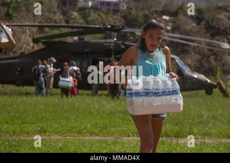 Bürger von Jayuga Essen und Wasser aus Ein HH-60 Black Hawk an die 101 Combat Aviation Brigade (CAB), Luftlandedivision (Air Assault), Puerto Rico, 4. Oktober 2017 zugewiesen. Die 101 CAB führt medizinische Evakuierung und Katastrophenhilfe FEMA im Wiederherstellungsprozess von Puerto Rico zu unterstützen nach der Verwüstung durch den Hurrikan Maria. (U.S. Armee Foto: Staff Sgt. Pablo N. Piedra) Stockfoto