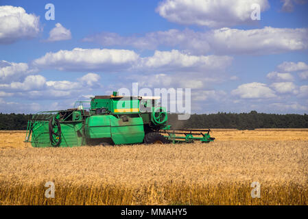 Maschine Mähdrescher Ernten auf dem Bauernhof Feld in sonniger Tag mit Wolken Stockfoto