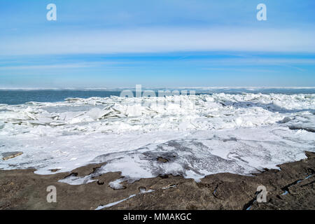 Die eisige Kälte und felsigen Ufer des Lake Erie im Nordwesten von Ohio. Große Blätter von gebrochenem Eis stapeln sich auf den Felsen. Stockfoto