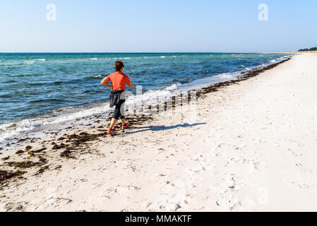 Falsterbo, Schweden - 28. April 2018: Reisen Dokumentarfilm von Alltag und statt. Frau zu Fuß am Sandstrand, während Ihre Hand zu ihr zurück halten als Stockfoto