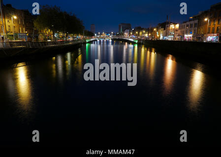 Nacht Langzeitbelichtung Blick auf Ha'Penny Bridge über den Fluss Liffey in Dublin mit bunten Reflexionen auf Wasser Stockfoto