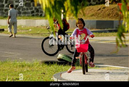 Madiun, Indonesien. 10. Mai, 2018. Kleine Kinder Erwachsene Radfahren pancal am Morgen Credit: Ajun Ally/Pacific Press/Alamy leben Nachrichten Stockfoto