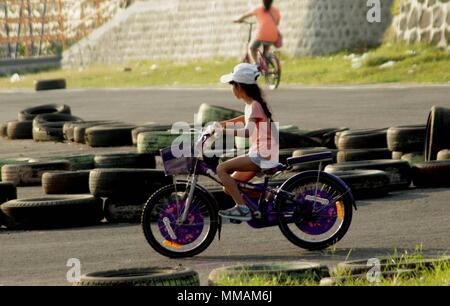 Madiun, Indonesien. 10. Mai, 2018. Kleine Kinder Erwachsene Radfahren pancal am Morgen Credit: Ajun Ally/Pacific Press/Alamy leben Nachrichten Stockfoto