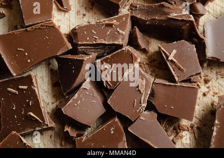 Overhead Nahaufnahme von Schokolade, grob gebrochen und auf einem wooding Schneidebrett verstreut. Stockfoto
