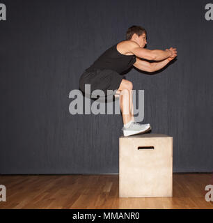 Junge muskulöse Mann, Kreuz-fit-Übung - springen Sie auf fit-Box Stockfoto