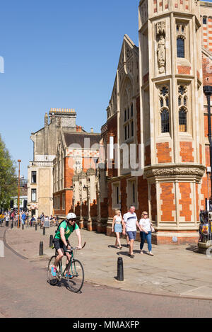 Cambridge, UK - April 2018. Menschen radfahren Neben alten Divinity School in St Johns Street, central Cambridge City Centre Stockfoto