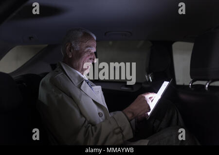 Unternehmer aus der Ferne Arbeiten auf Geschäftsreise, mit digitalen Tablet, sitzt im Taxi Auto. Stockfoto